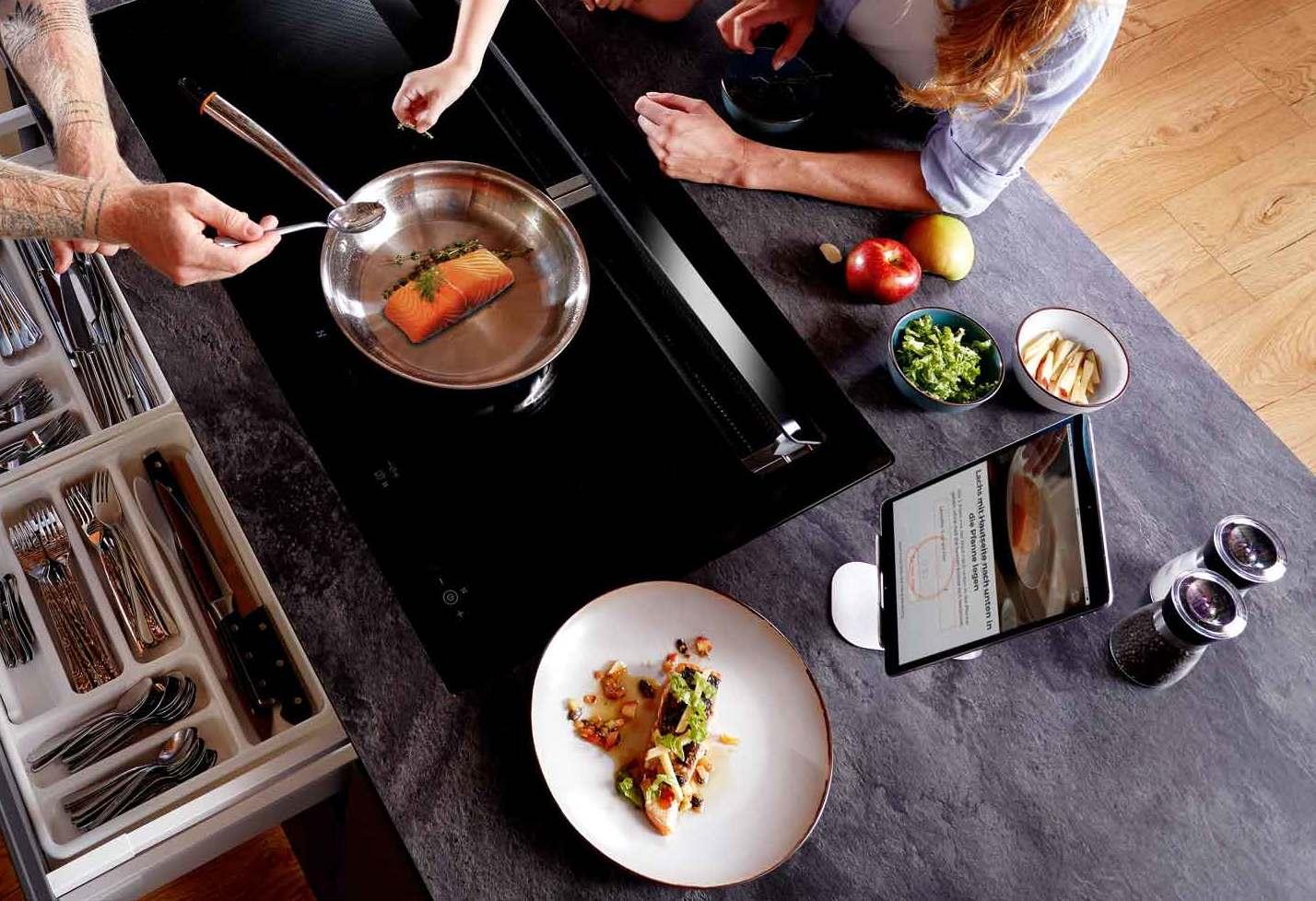 Oranier Induktionskochfeld mit Edelstahlpfanne und Lachsfilet, Tablet zeigt Rezeptanzeige